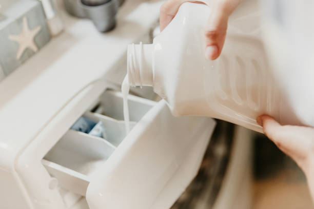 verser le liquide de lavage dans la machine à laver - liquide vaisselle photos et images de collection