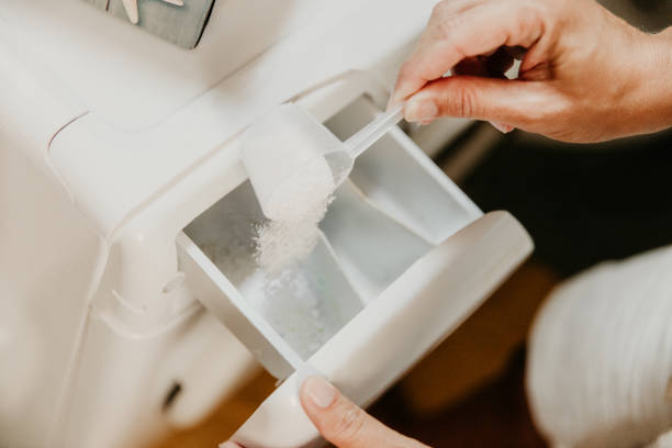 Pouring washing powder in washing machine Woman pouring washing powder detergent in washing machine at home bleach stock pictures, royalty-free photos & images