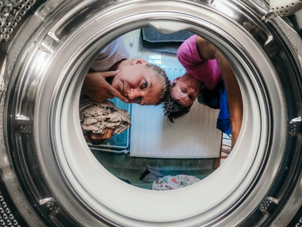 istock Couple holding clothes and looking into washing machine 1297415784