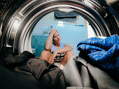 Upset woman looking at clothes in washing machine at bathroom