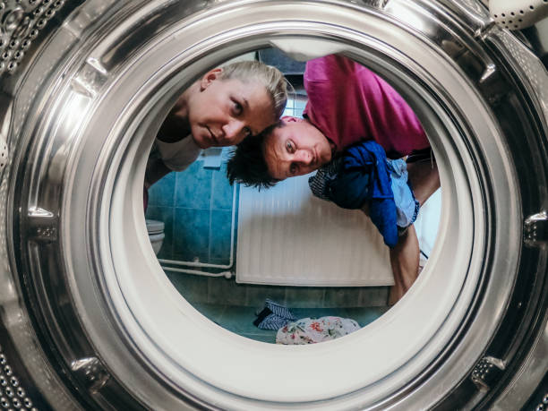 Inside of washing machine/dryer Couple at home doing laundry putting clothes in the washing machine in bathroom laundry husband housework men stock pictures, royalty-free photos & images