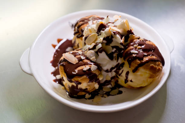 istock Profiteroles with ice cream, almond and chocolate on a plate 1297415847