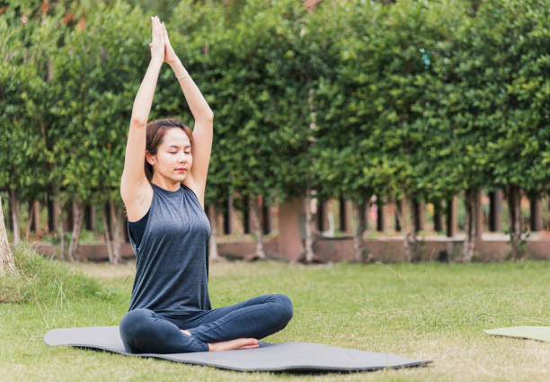 istock woman practicing yoga outdoors in meditate pose sitting on green grass 1297416451