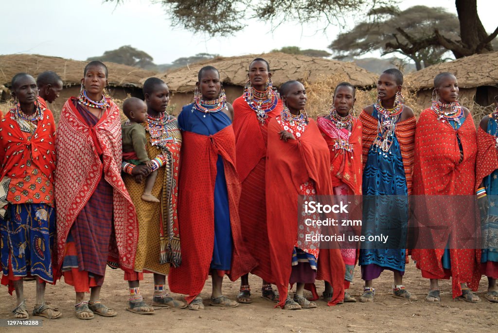 African women from Masai tribe. Kenya, Africa Masai Mara, Kenia - August 23, 2010: Group of unidentified african women from Masai tribe  in multi-colored cotton dresses and beaded jewelry in a local village near Masai Mara National park. Africa Maasai People Stock Photo