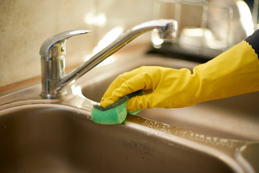 Cropped shot of an unrecognizable woman cleaning the kitchen sink