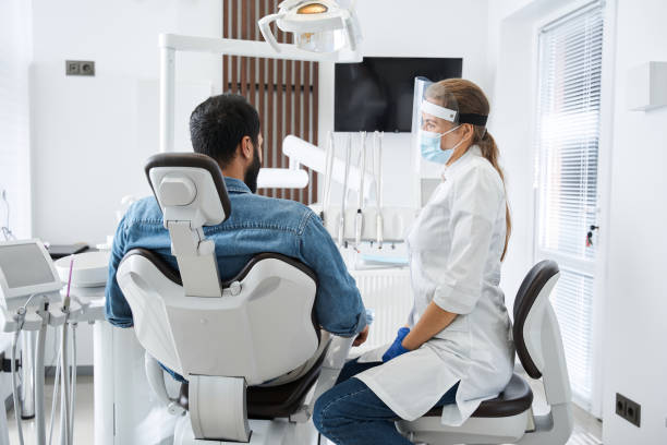 istock Dentist in protective mask examining her male patient 1297420695