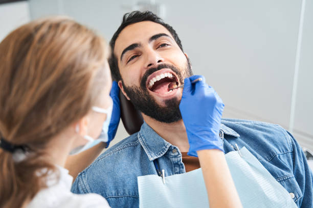 guapo hombre caucásico sentado en sillón en la oficina del dentista - medical exam dental hygiene caucasian mask fotografías e imágenes de stock
