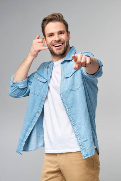 istock man in jeans shirt making a call me gesture standing over studio grey background 1297420825