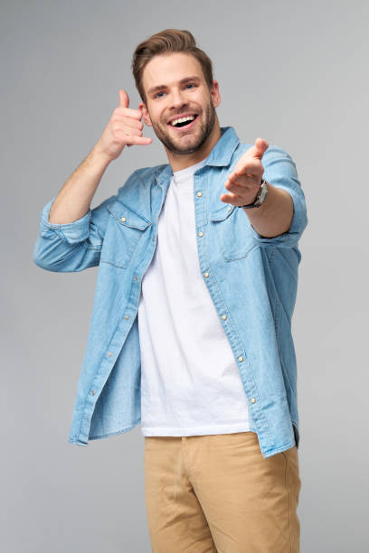 istock man in jeans shirt making a call me gesture standing over studio grey background 1297420830