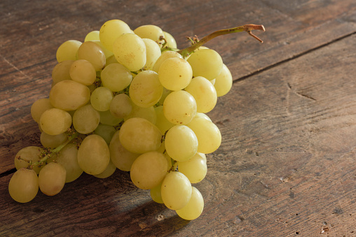 A bunch of organic Muscat grapes on an old wood tabletop