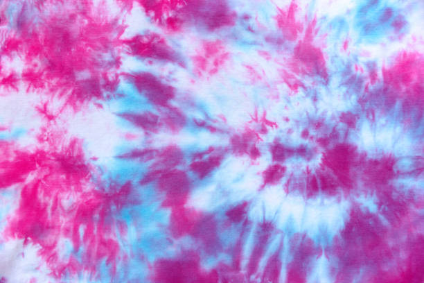 Pink and blue hand made tie die pattern on white textile.