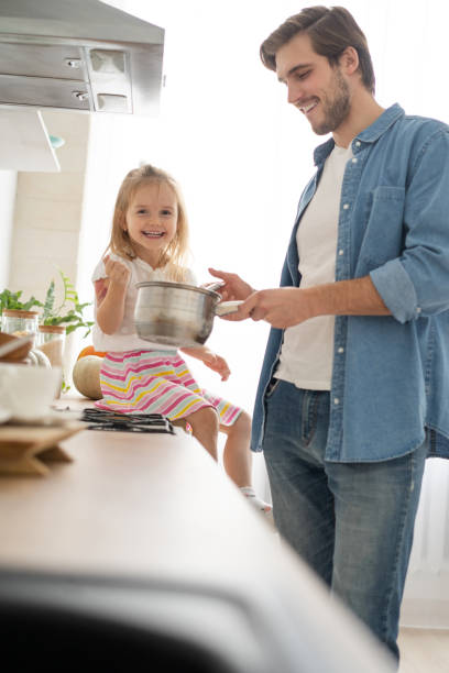 istock Daughter Helping Father To Cook Meal In Kitchen. 1297423522
