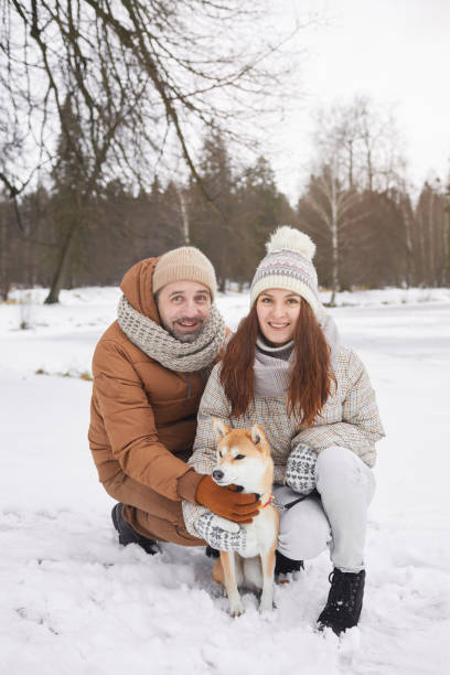 istock Smiling Couple Posing with Dog in Winter 1297424215