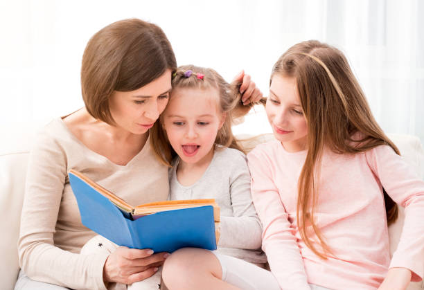 istock Mom and daughters reaading children's book 1297425512