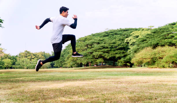 istock Handsome young man athlete runner with energy exercise training and jumping outdoors with big green tree in the public park. Active healthy and motivation lifestyle and ambition Concept 1297425992