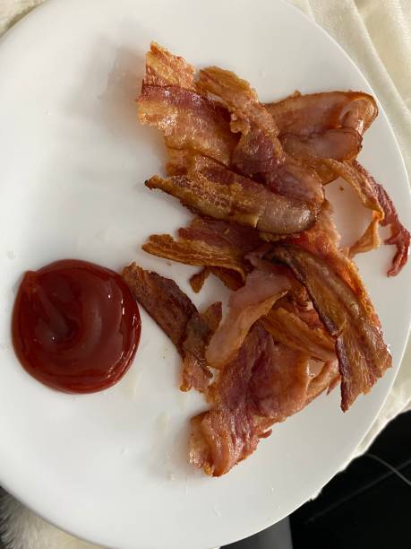 istock Close up of freshly cooked greasy bacon on a white plate 1297427582