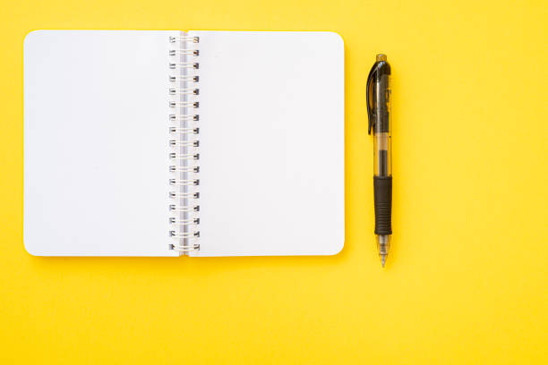 istock Notebook with ring binder with pen on it, isolated on yellow backdrop with copy space. Concept of writing. 1297427700