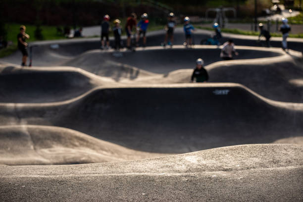 skatepark per ciclisti, pattinatori in linea, immerso nell'erba fuori di giorno - skateboard park foto e immagini stock