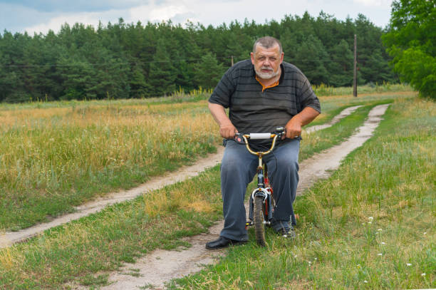 Old man imagine that he is young when playing with kids bicycle