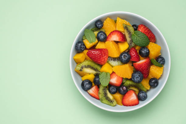 Fruit salad in bowl. Mango, kiwi, orange, apple, strawberry and blueberry berries stock photo