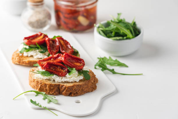 istock Bruschetta with sun dried tomatoes and arugula.  White background, close-up, top view 1297429424