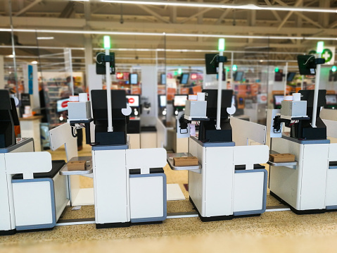 Color image depicting self checkout terminals inside a superstore.