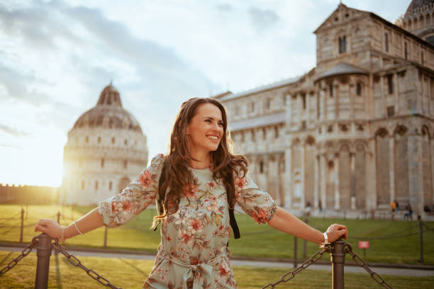 lächelnde trendige frau in floralen kleid genießen promenade - pisa tuscany italy baptistery stock-fotos und bilder