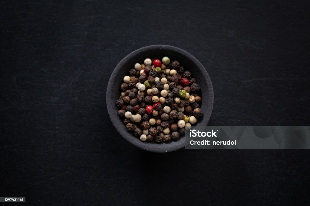 Pepper in bowl on dark background Color whole peppercorns  in small bowl on dark background. Pepper - Seasoning Stock Photo