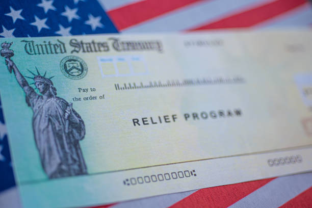 istock COVID-19 economic Stimulus check on blurred USA flag and sun light background. Relief program concept. 1297433134