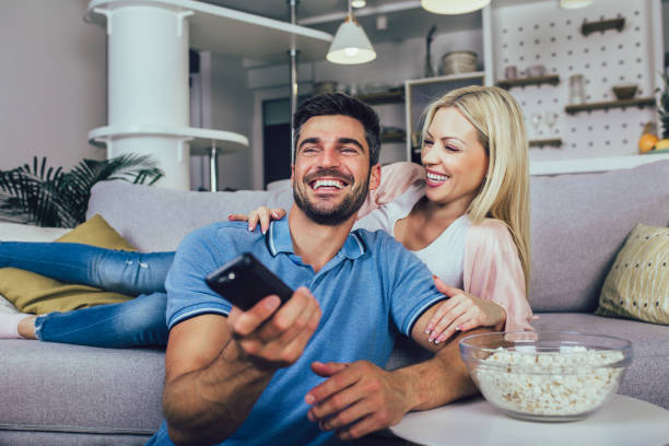istock Young couple watching TV on a sofa at home 1297433962