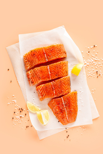 Slices of fresh salmon with spices on parchment paper