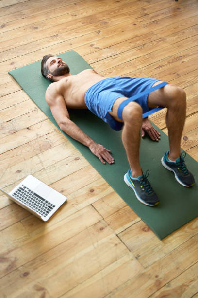 istock Athletic young man using fitness band during workout at home 1297435691