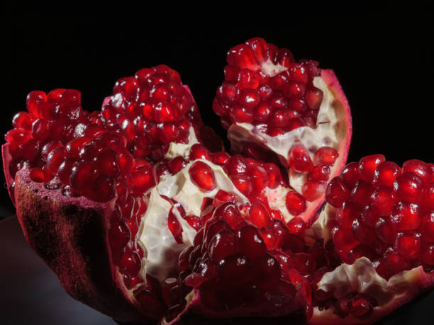 istock Pomegranate broken into pieces close-up on a black background. 1297435723