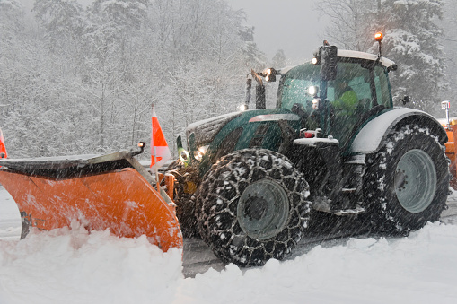 Snowplow clears snow at an intersection of a highway during heavy snowfall.