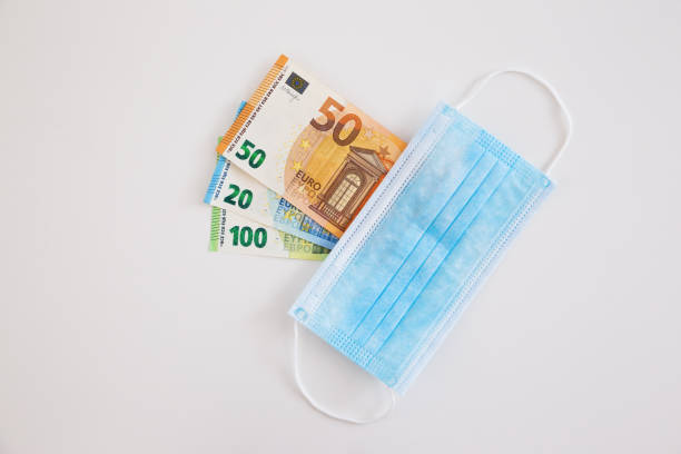 istock Surgical face mask covering cash on white background. 1297436149