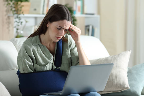 donna handicappata preoccupata che legge notizie su laptop - teenager laptop computer anger foto e immagini stock