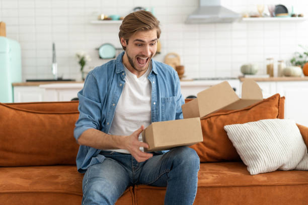 istock Happy man customer unpacking cardboard box receive open post mail delivery package 1297439465