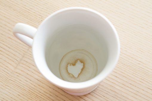 A cup of tea with the grounds at the bottom of it creating the silhouette of a heart