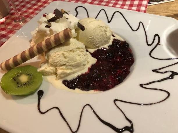 istock Vanilla ice cream with cranberries compote kiwi chocolate flakes and pastry roll 1297441903