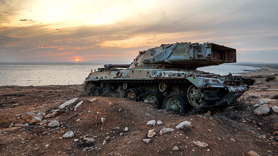 Abandoned military army tank vehicle at sunset in the coast. Environmental pollution