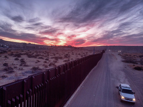 Aerial Drone View Of The Border Wall Dividing El Paso, Texas And Puerto De Anapra, In The Ciudad Juarez, Mexico At Sunset