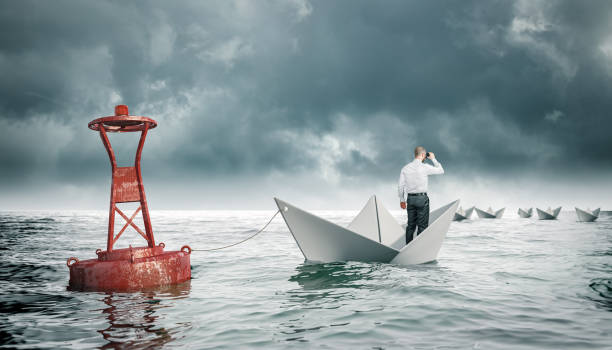 istock man with binoculars on paper boat tied to a buoy. 1297444657