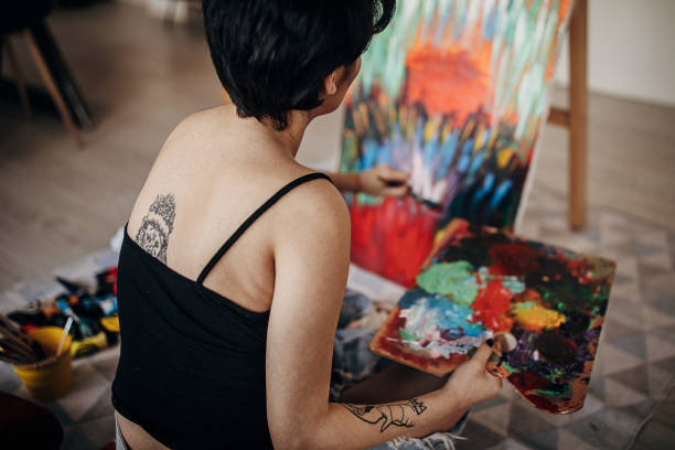 istock Tattooed female painter painting on the floor 1297445177