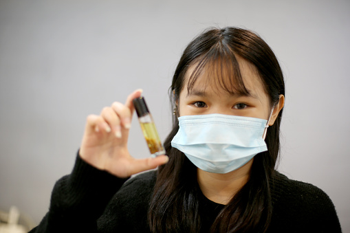 A teenage girl is holding handmade perfume using essential oil.