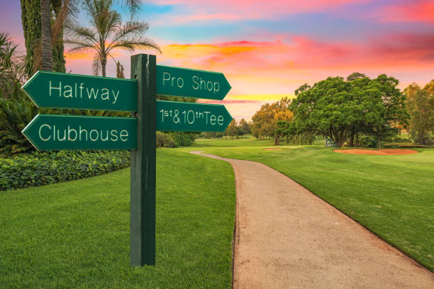 Golf course direction sign and pathway next to the fairway Golf course direction sign and pathway next to the fairway and colourful sunset in the background country club stock pictures, royalty-free photos & images