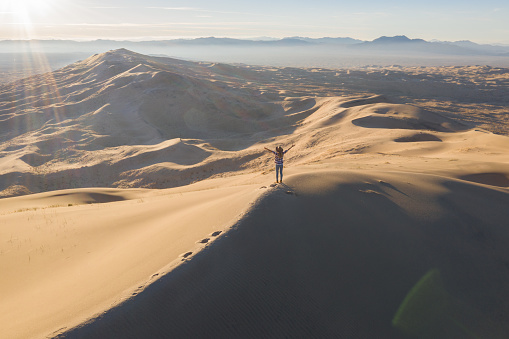 She stands on top of sand dune, looks at view.
Mojave desert, USA