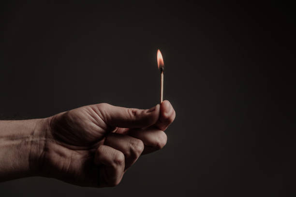 istock burning match in men's fingers, on a dark background 1297453707