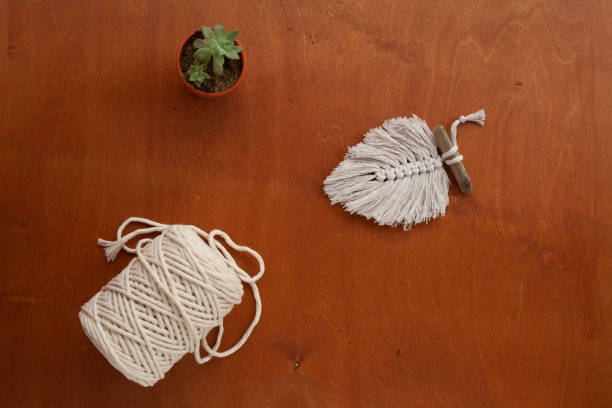 istock a ball of macrame thread and a feather on a wooden table 1297454038