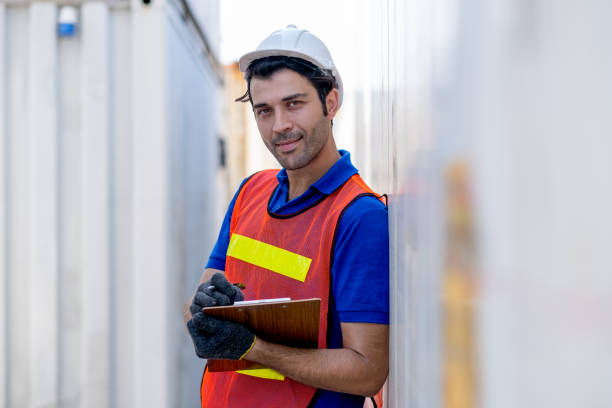 istock Cargo container worker or foreman hold clipboard and look to camera and stand in workplace area 1297455493