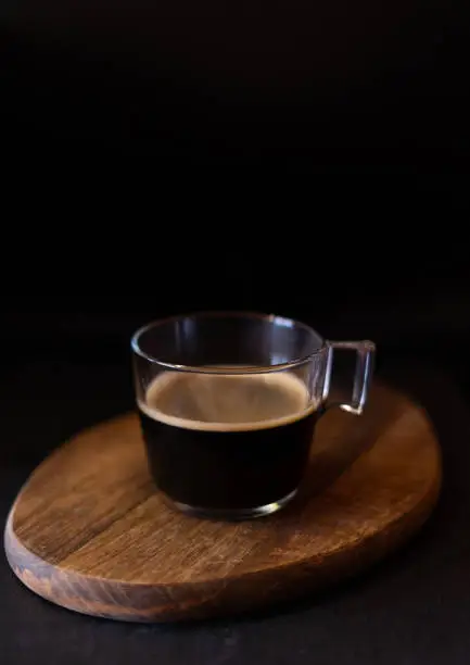Cup of coffee on a wooden table with black background.